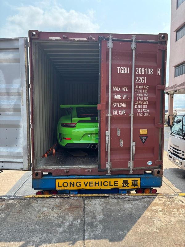 Green Porsche 911 GT3 RS loaded in a shipping container