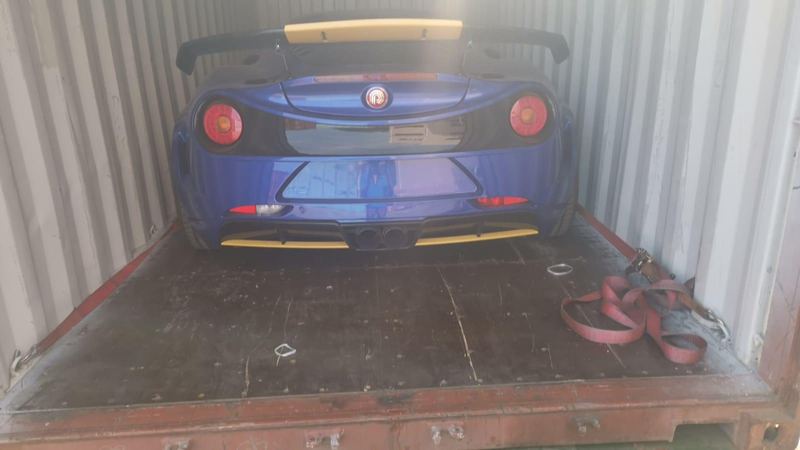 Blue sports car secured in a shipping container