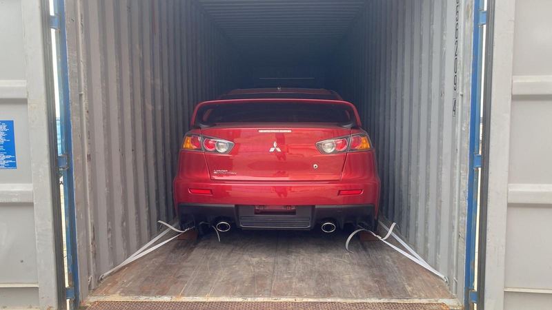 Red Mitsubishi Lancer Evolution in a shipping container